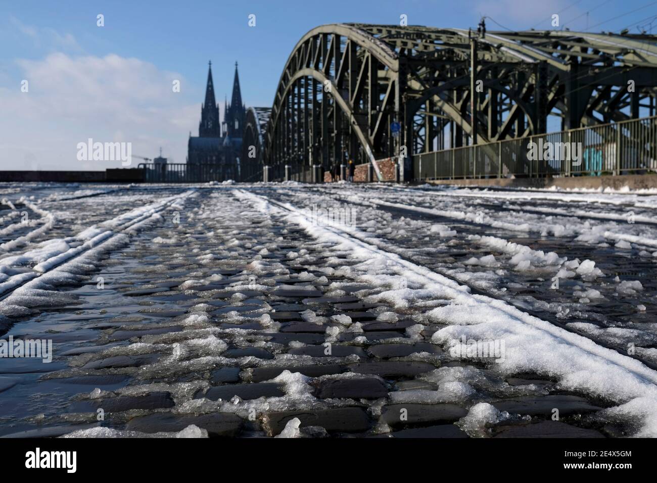 Schmelzender Schnee auf einem gepflasterten Weg in Köln, Deutschland, mit dem berühmten Dom im Hintergrund Stockfoto