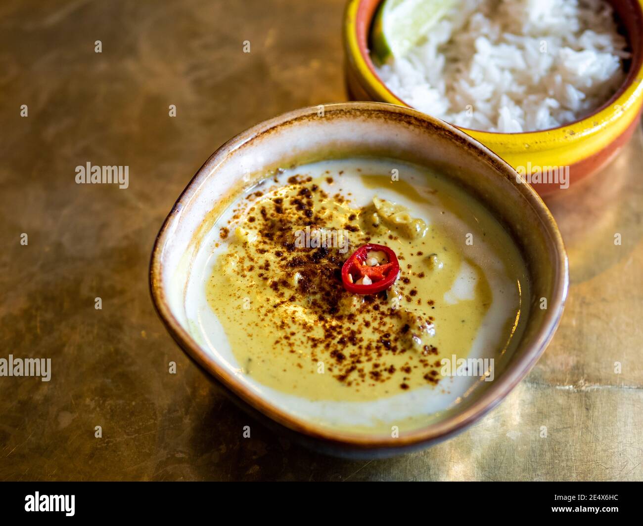 Gelbes Curry mit Blumenkohl und Kichererbsen und Reis auf Metall-Tischplatte Hintergrund. Indisches Essen. Vegetarisches Curry mit Platz für Text oder Design Stockfoto