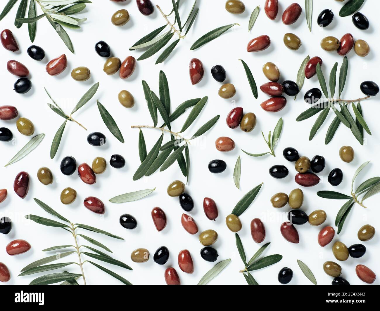 Schönes Muster mit grünen, schwarzen und roten Oliven und Oliven Baum Blätter und Zweige auf weißem Hintergrund. Oliven und Zweige als Muster, Draufsicht oder Flachlage mischen. Stockfoto