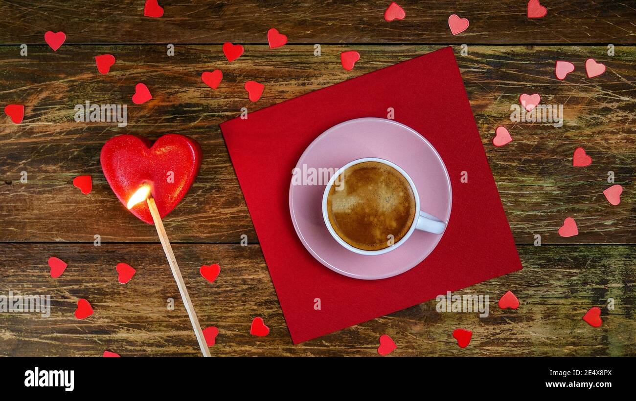 Tasse Kaffee auf roter Serviette und zünden herzförmige Kerze mit langem Streichholz an. Ein romantischer Tag. Valentinstag oder Frauentag Konzept. Draufsicht. Flach liegend Stockfoto
