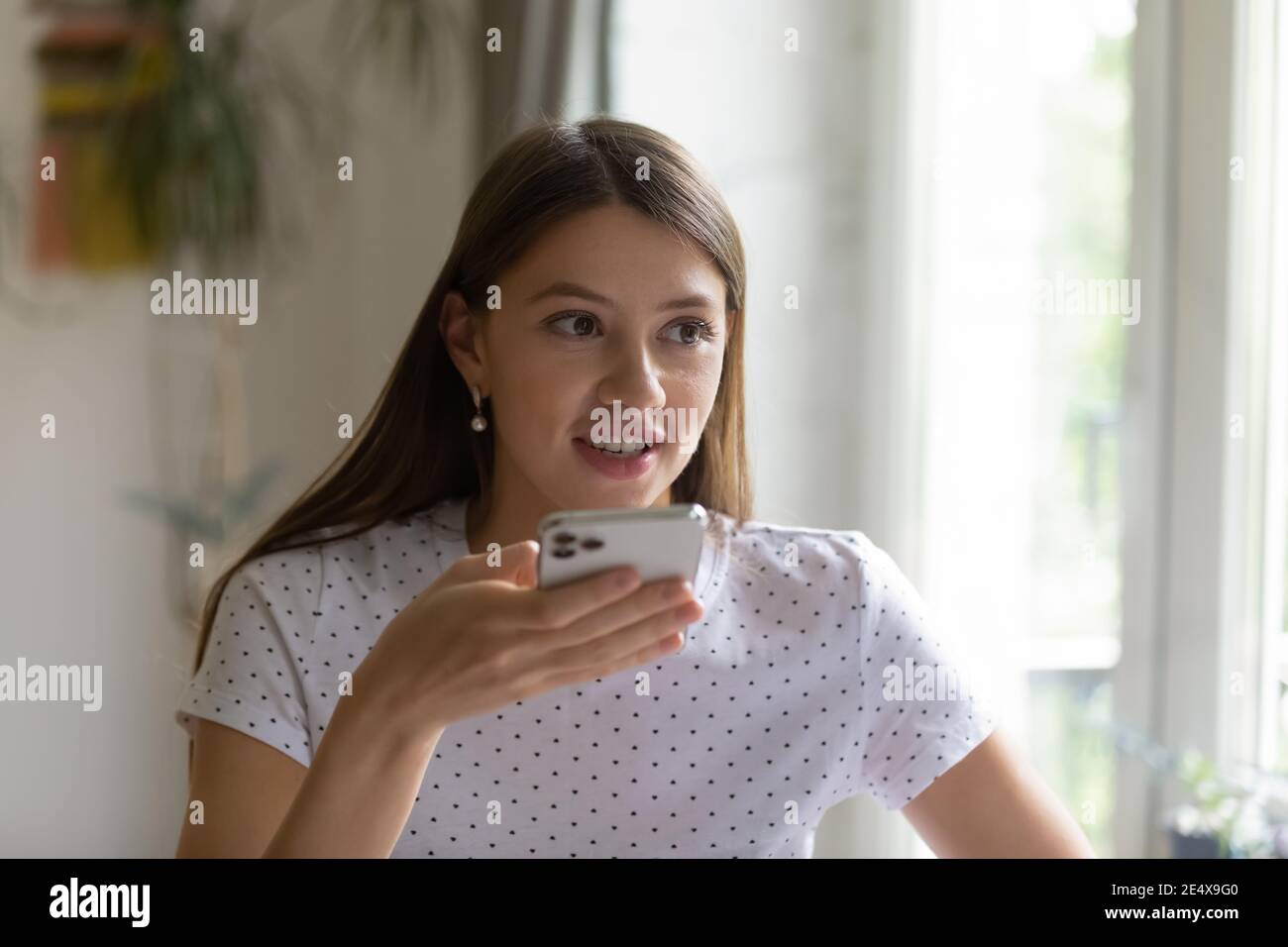 Lächelnde junge Dame mit modernem Handy, das Audio-Nachricht aufzeichnet Stockfoto