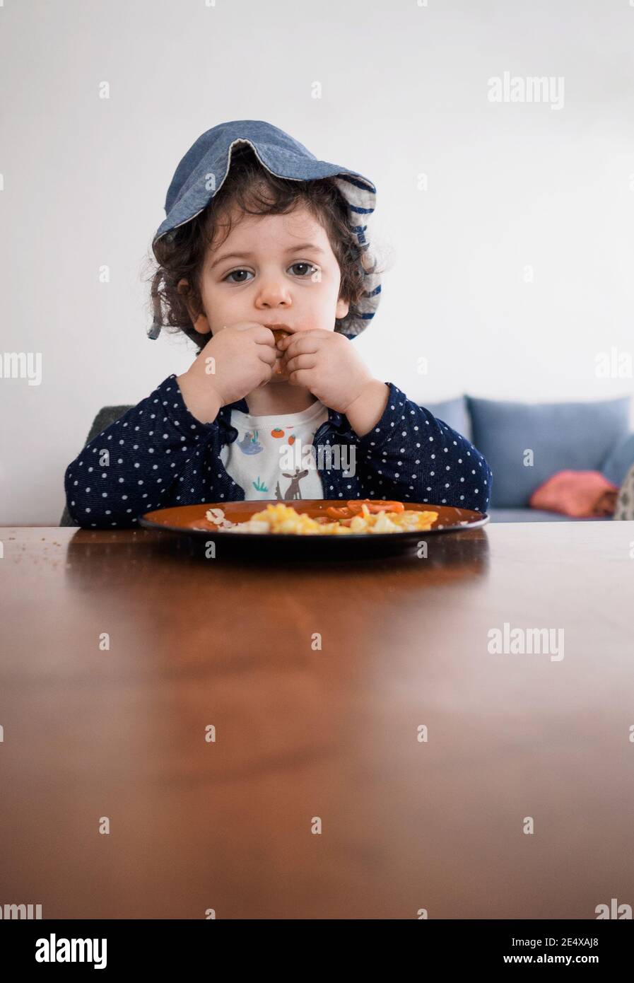 Junge Kleinkind sitzt an einem Tisch essen mit ihren Händen Stockfoto