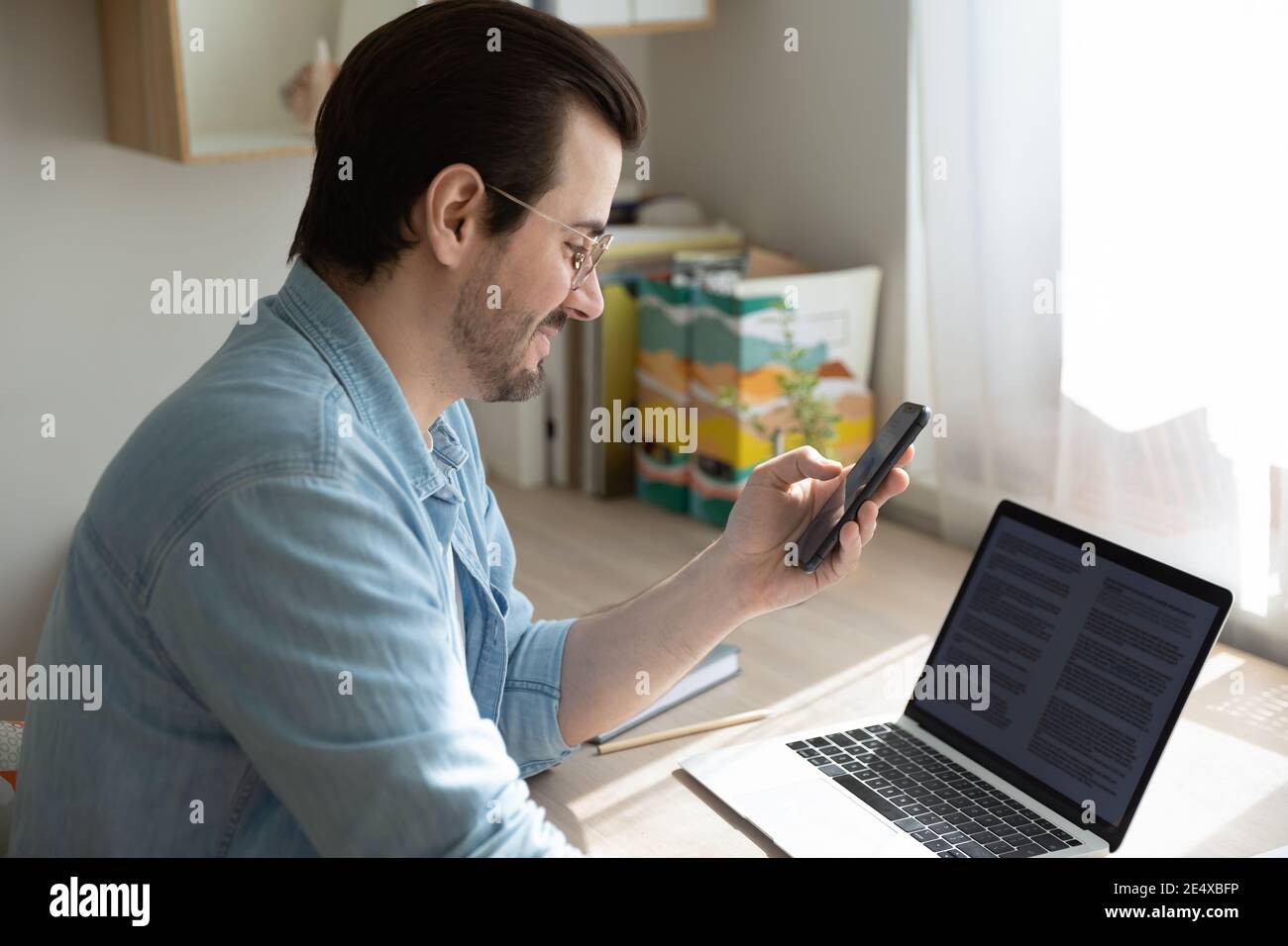 Junger Mann sendet Dateien von Zelle zu pc mit App Stockfoto
