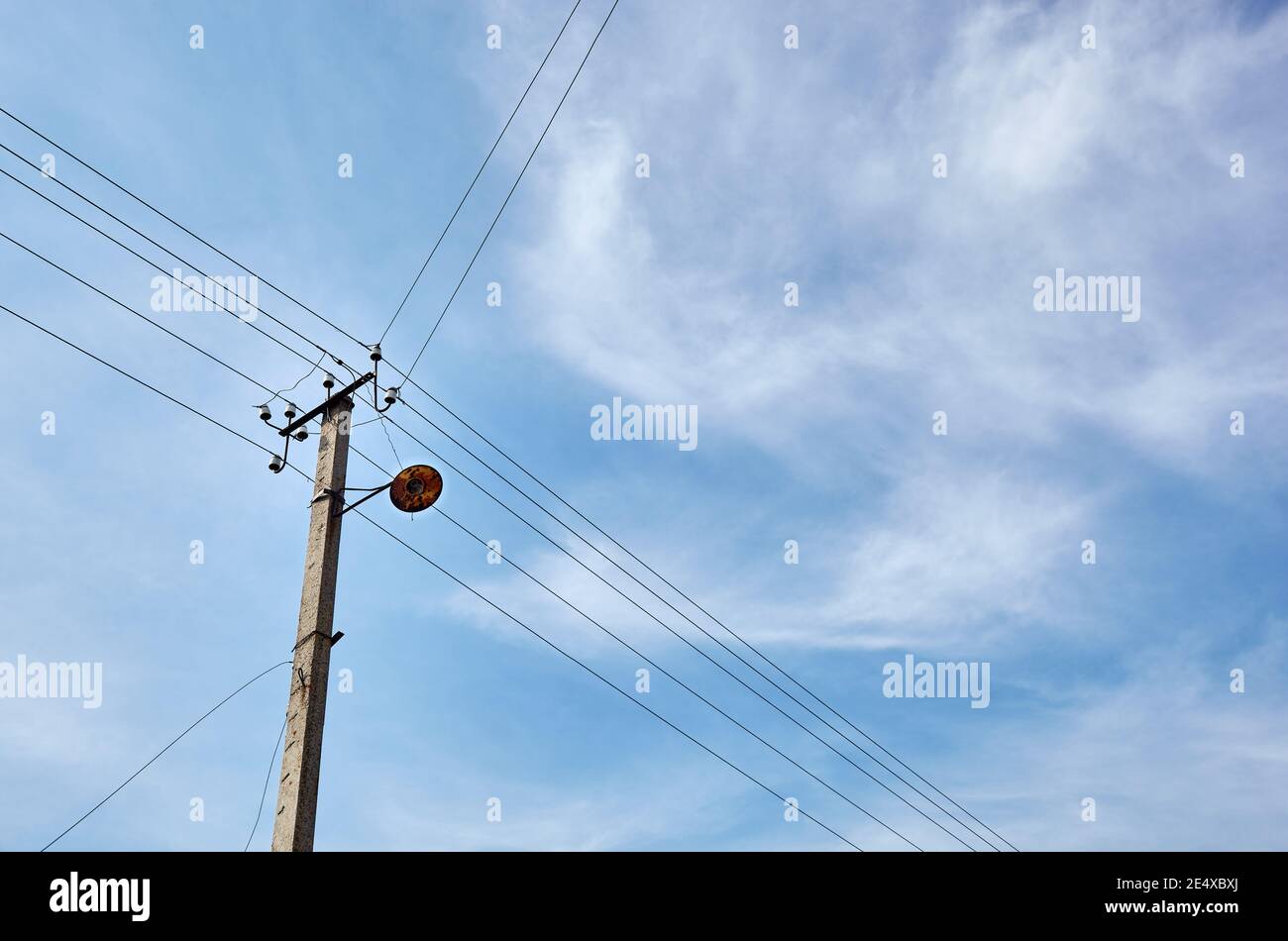 Nahaufnahme der alten Säule an einem Sommertag. Stromlinienpfosten mit Stromkabeln gegen einen klaren blauen Himmel Stockfoto