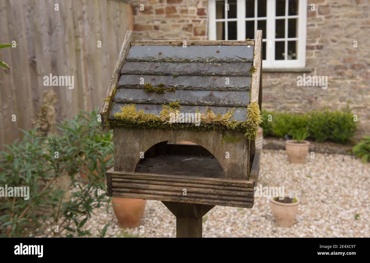 Traditionelles verwittertes hölzernes Vogelhaus mit Schiefer-Fliesendach, bedeckt mit Moos in einem Landhausgarten in Rural Devon, England, Großbritannien Stockfoto