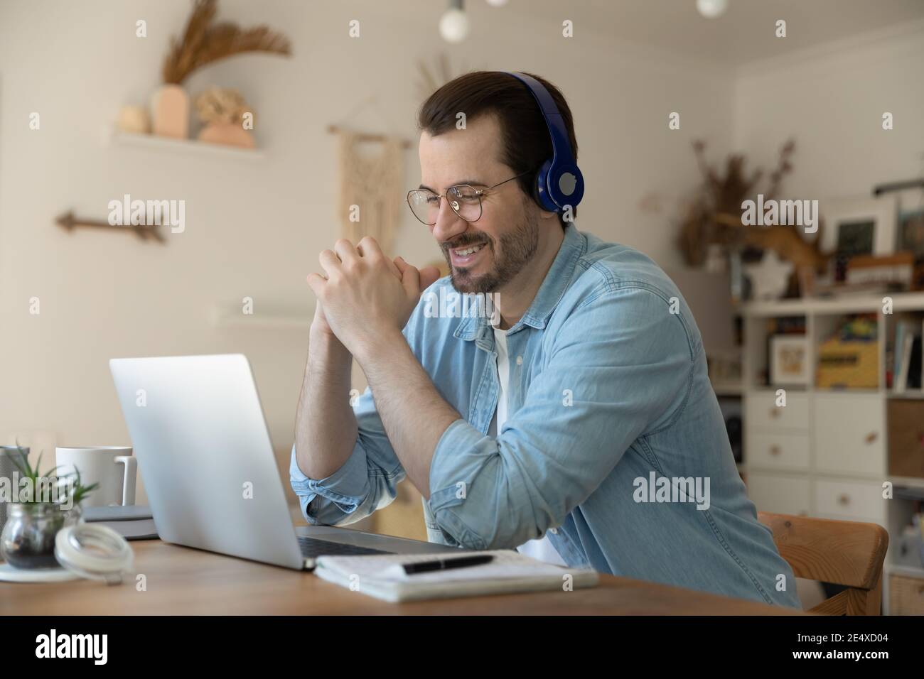 Glücklich junger Mann Student sitzt vor pc in Kopfhörer-Set Stockfoto