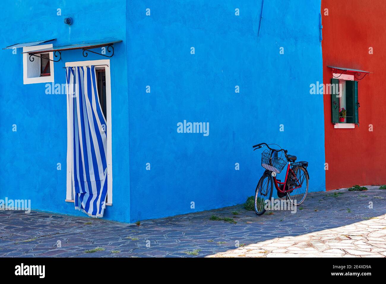 Fahrrad vor typischen Häusern in lebendigen blauen und roten Farben in Burano - kleine Stadt in Venetien, Italien gemalt. Stockfoto