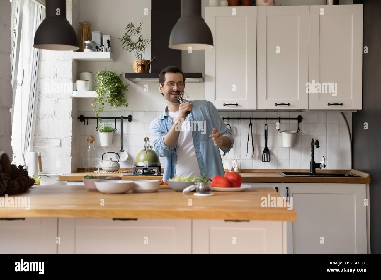 Glücklich junger Mann Kochen romantisches Abendessen Gesang in imaginären Mikrofon Stockfoto