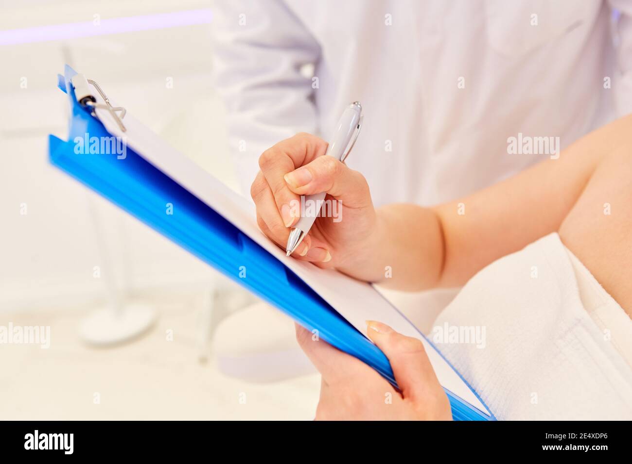 Die Hand des Patienten unterschreibt den Behandlungsvertrag für eine Kosmetik Chirurgie Stockfoto