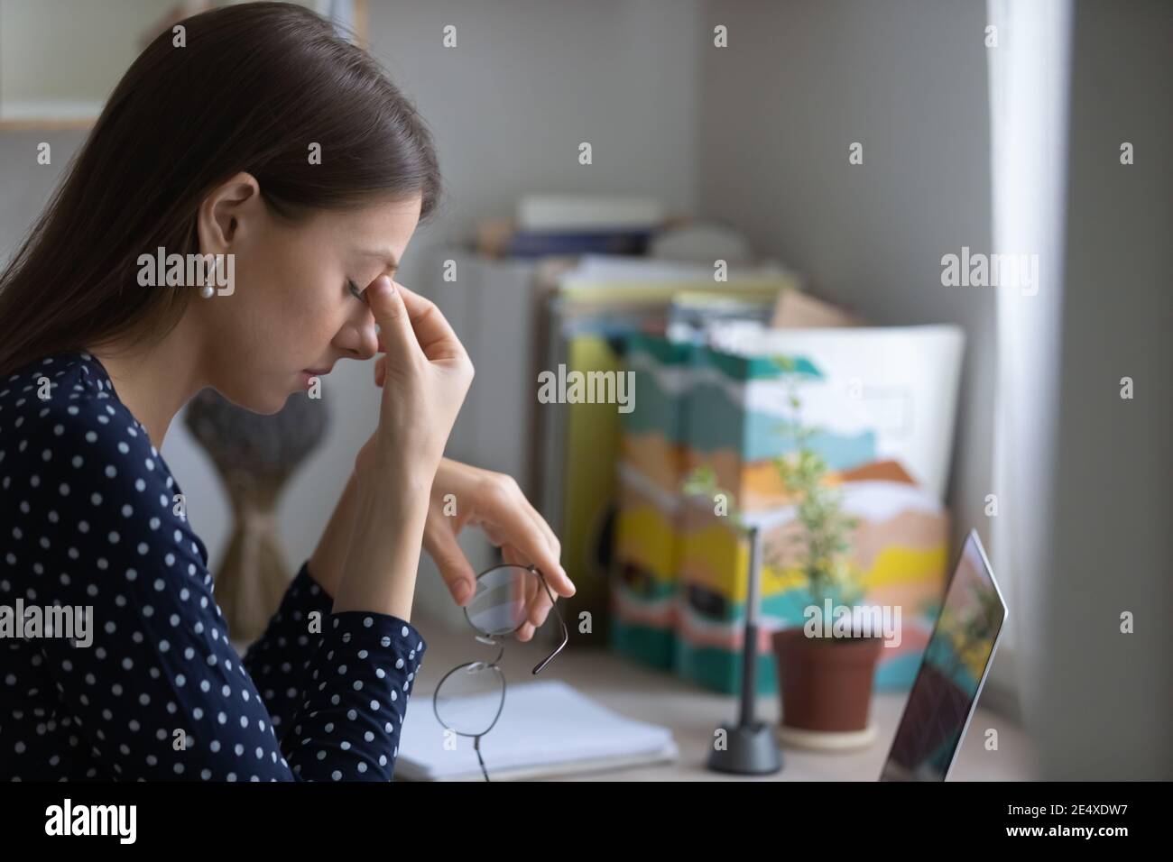 Junge Frau überarbeitet durch Computer, die Brille abreibt Nase Stockfoto