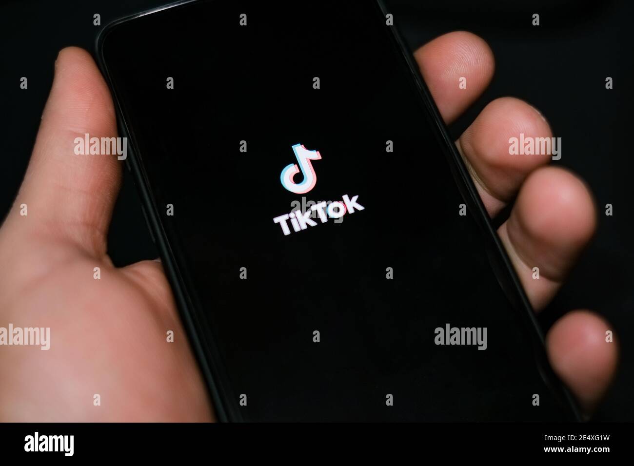 Junger Mann halten ein Smartphone, während mit tiktok App, soziale Netzwerk Technikabhängigkeit Stockfoto