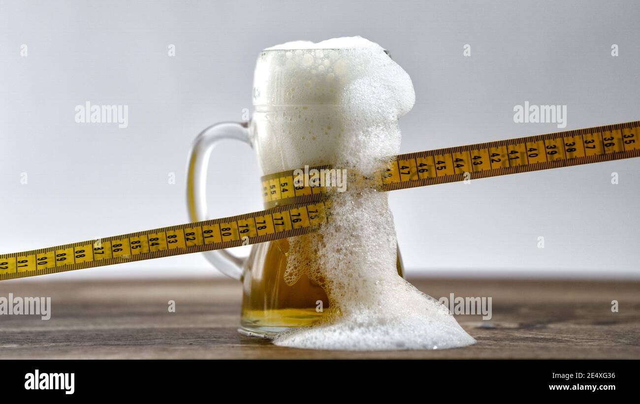 Maßband um ein Glas frisch gezapftes Bier gewickelt. Diät Gewichtsverlust Konzept schlechte Gewohnheit Bier Bauch Fettleibigkeit Alkohol süchtig Stockfoto