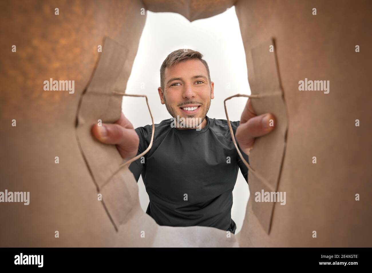 Glücklicher lächelnder Mann, der mit dem Mitnehmen in die Papiertüte schaute Essen aus dem Restaurant während des Coronavirus-Ausbruchs Stockfoto