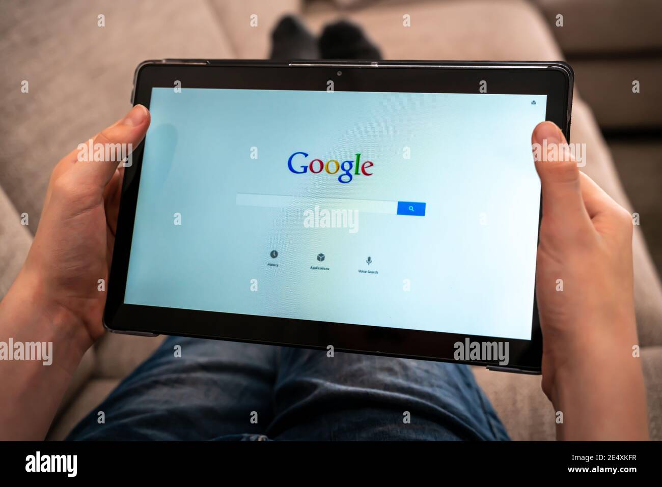 Person mit Tablet mit Google-Suche-App, um das Web zu durchsuchen. Stockfoto