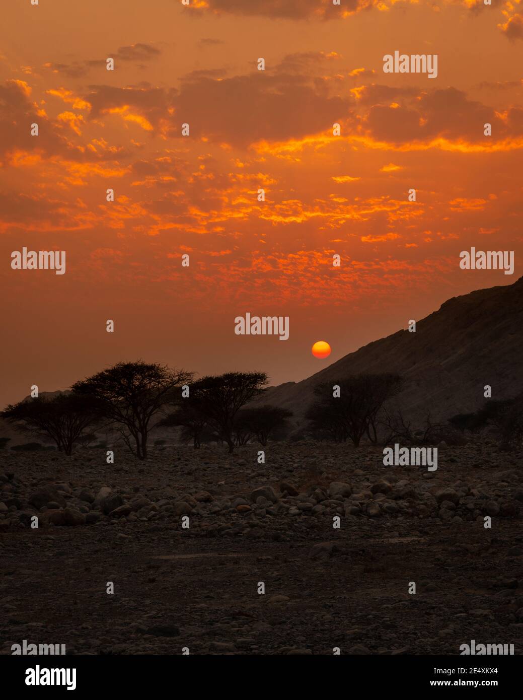 Eine wunderschöne Szene des Sonnenuntergangs hinter den kargen Bergen der Wüste in Ras Al Khaimah, Vereinigte Arabische Emirate. Stockfoto