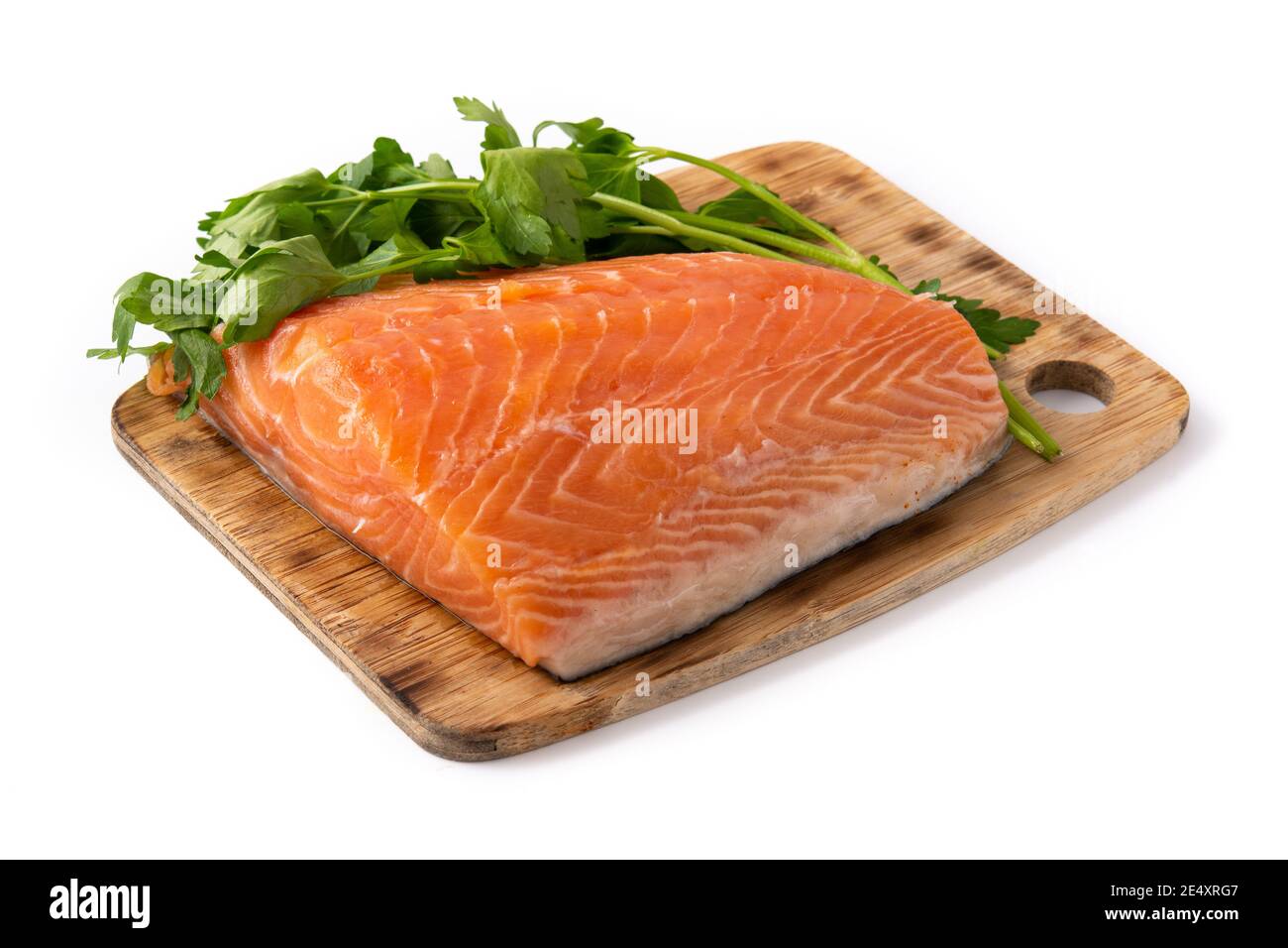 Rohes Lachsfilet und Petersilie auf Schneidebrett isoliert auf Weißer Hintergrund Stockfoto
