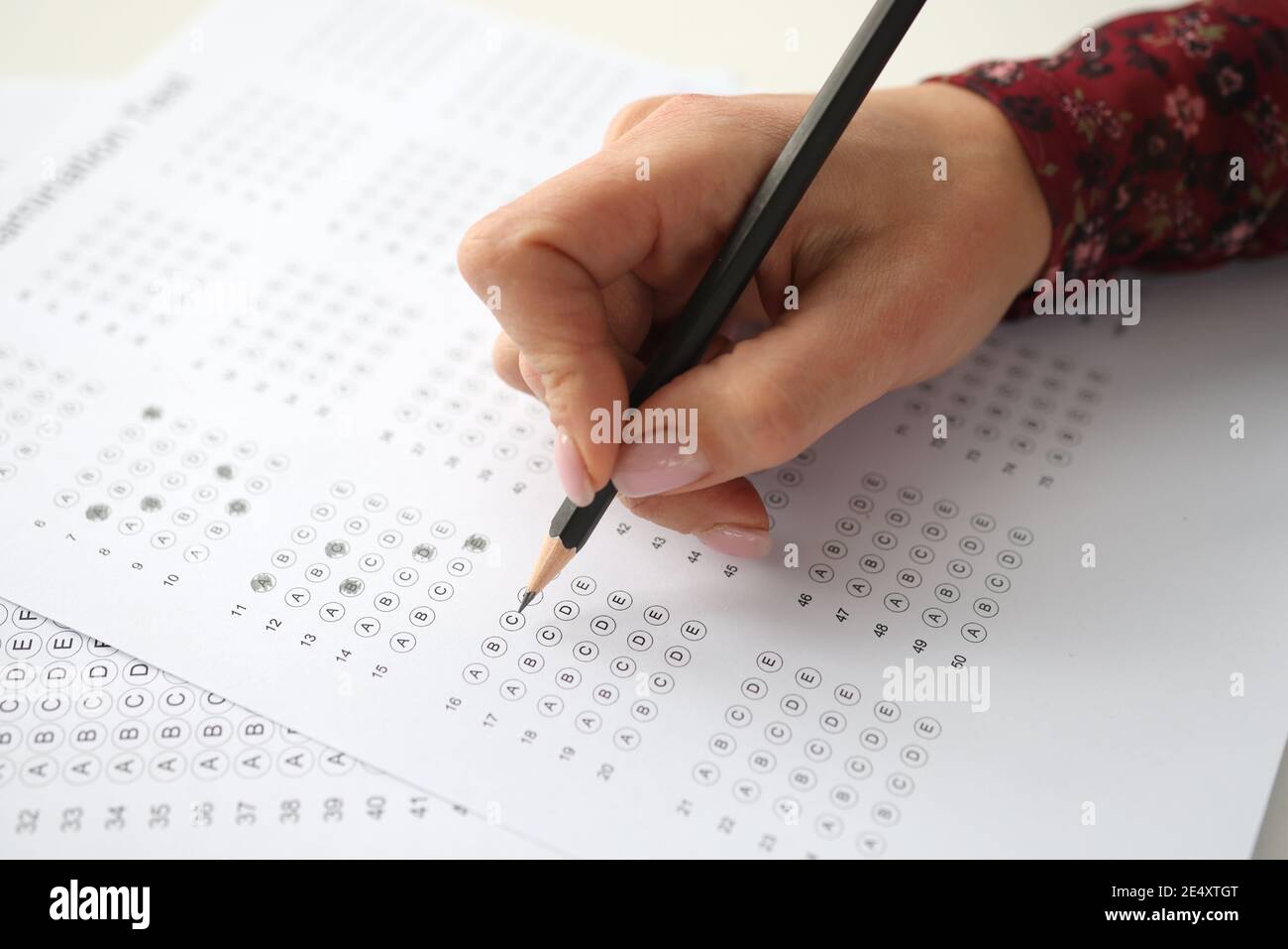 Weibliche Hand hält Bleistift und markiert Antworten auf Test Stockfoto