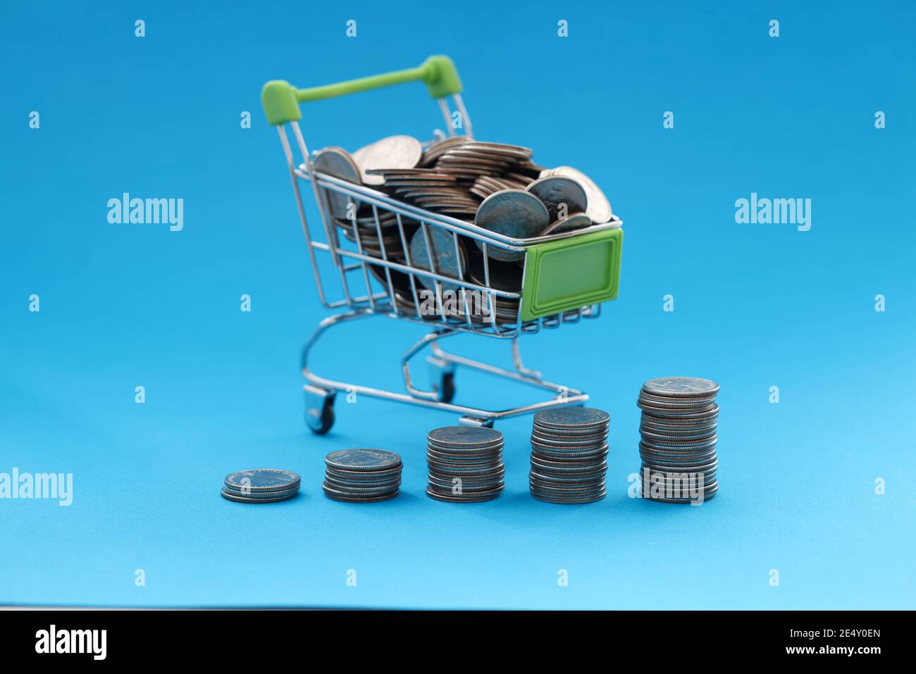 Der Warenkorb enthält Münzen auf blauem Hintergrund Stockfoto