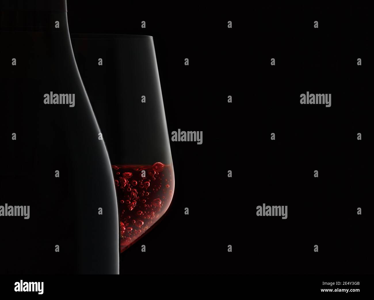 Nahaufnahme von Flasche und Weinglas mit Rotwein auf schwarzem Hintergrund. Stockfoto