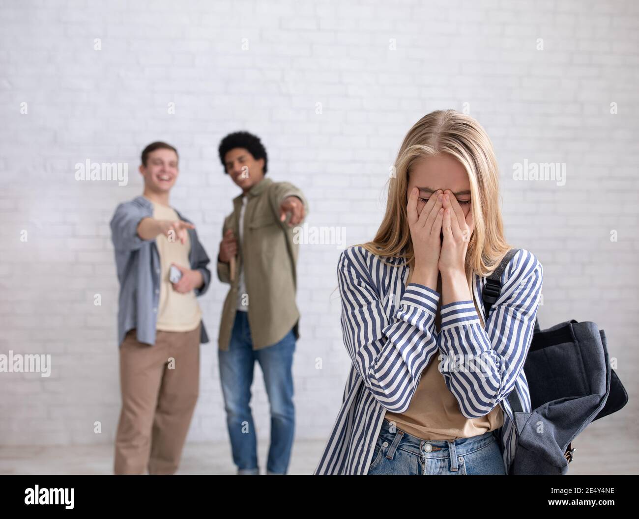 Europäische und afroamerikanische Teenager Zoomers Jungs lachen am Weinen Frau mit Rucksack in der Schule oder Hochschule Stockfoto