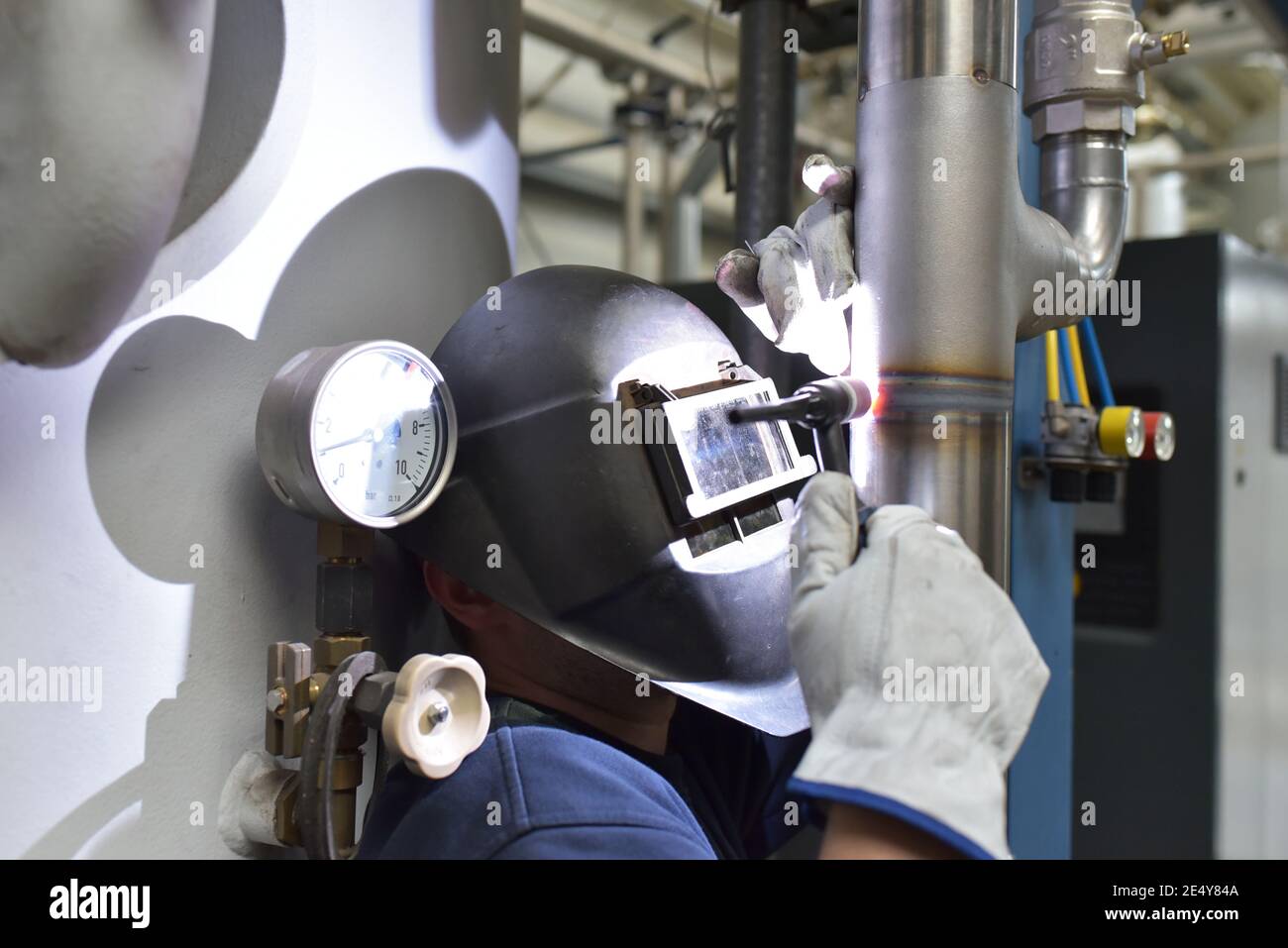 Schweißer arbeitet im Stahlbau und repariert ein Industriewerk Stockfoto