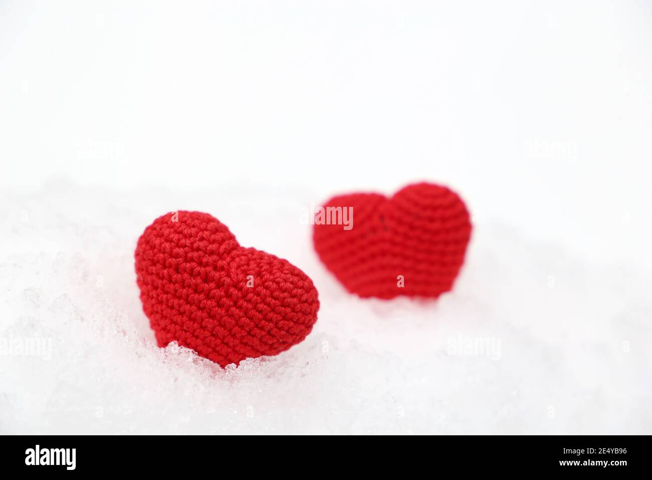 Valentine Herzen im Schnee. Zwei rote Strickherzen im Winter, Symbol der romantischen Liebe, Hintergrund für den Urlaub Stockfoto