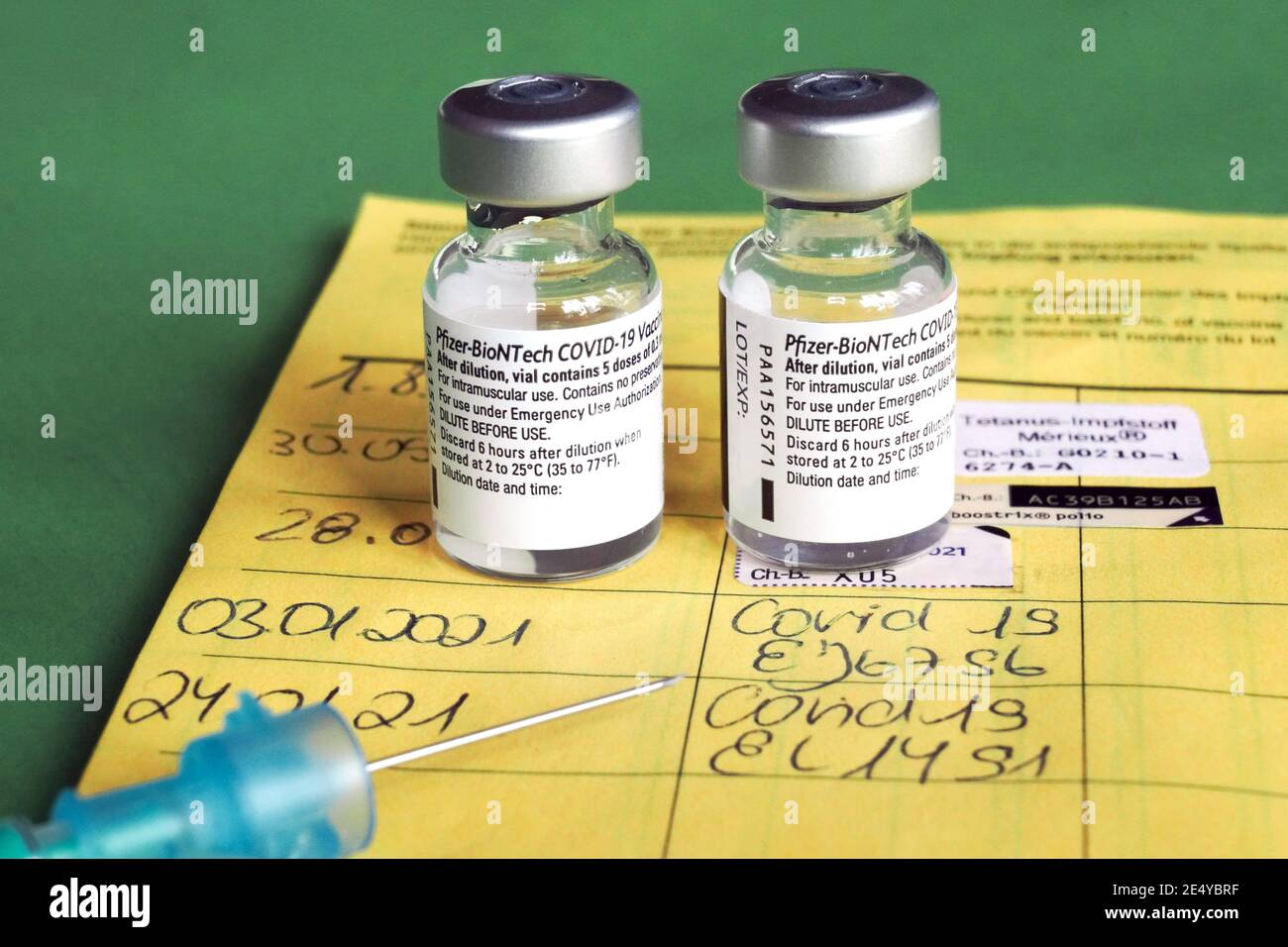 Symbolbild Corona-Impfung. Zwei Impfdosen, Impfritze und der Eintrag der ersten und zweiten Corona-Impfdung in einem Impfpass einer mit dem COVID-19-mRNA-Impfstoff der Firma BioNTech geimpften Person. Dortmund, 25.01.2021 --- Corona-Impfsymbole. Zwei Impfdosen, Impfspritze und Eintrag der ersten und zweiten Coronaimpfung in einen deutschen Impfpass einer mit dem COVID-19 mRNA-Impfstoff von BioNTech geimpften Person. Dortmund, den 25th. Januar 2021 Stockfoto