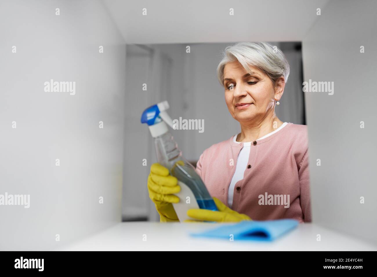 Ältere Frau Reinigungsgestell mit Waschmittel zu Hause Stockfoto