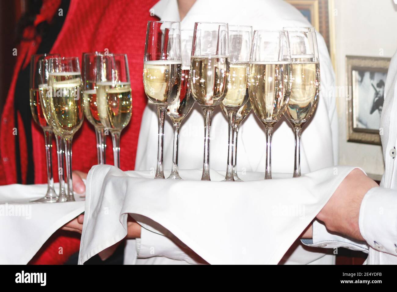 Ein Kellner gibt den Gästen bei einer Firmenfeier Champagner-Gläser. Getränke Stockfoto