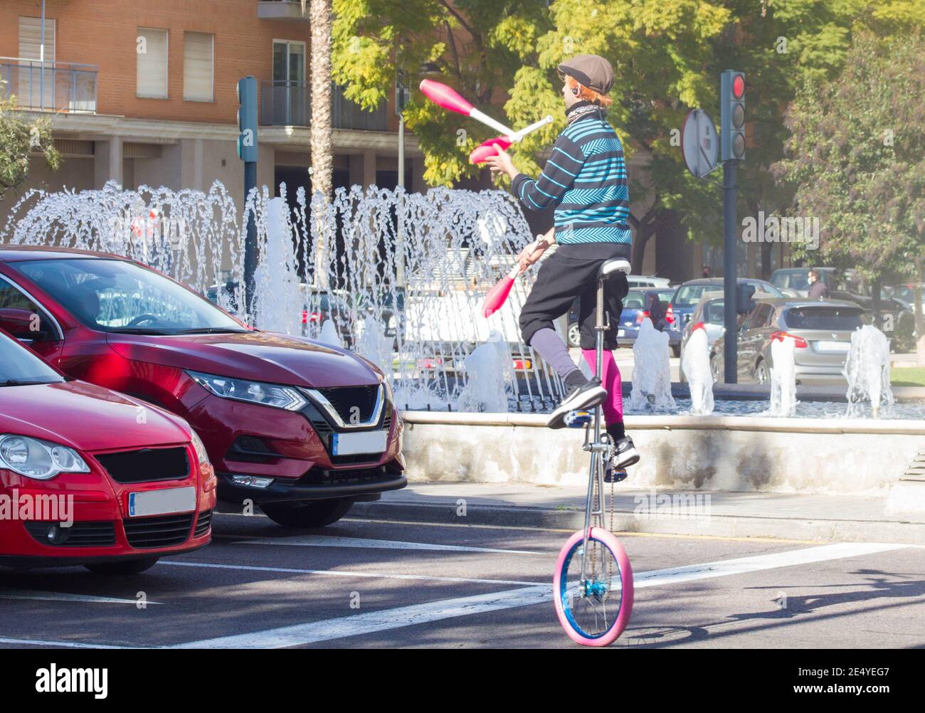 VALENCIA, SPANIEN - 15. Jan 2021: Ein Puppenspieler-Clown nutzt das rote Licht, um Fahrern auf öffentlichen Straßen eine Jongliershow zu bieten, um sich einen Livin zu verdienen Stockfoto