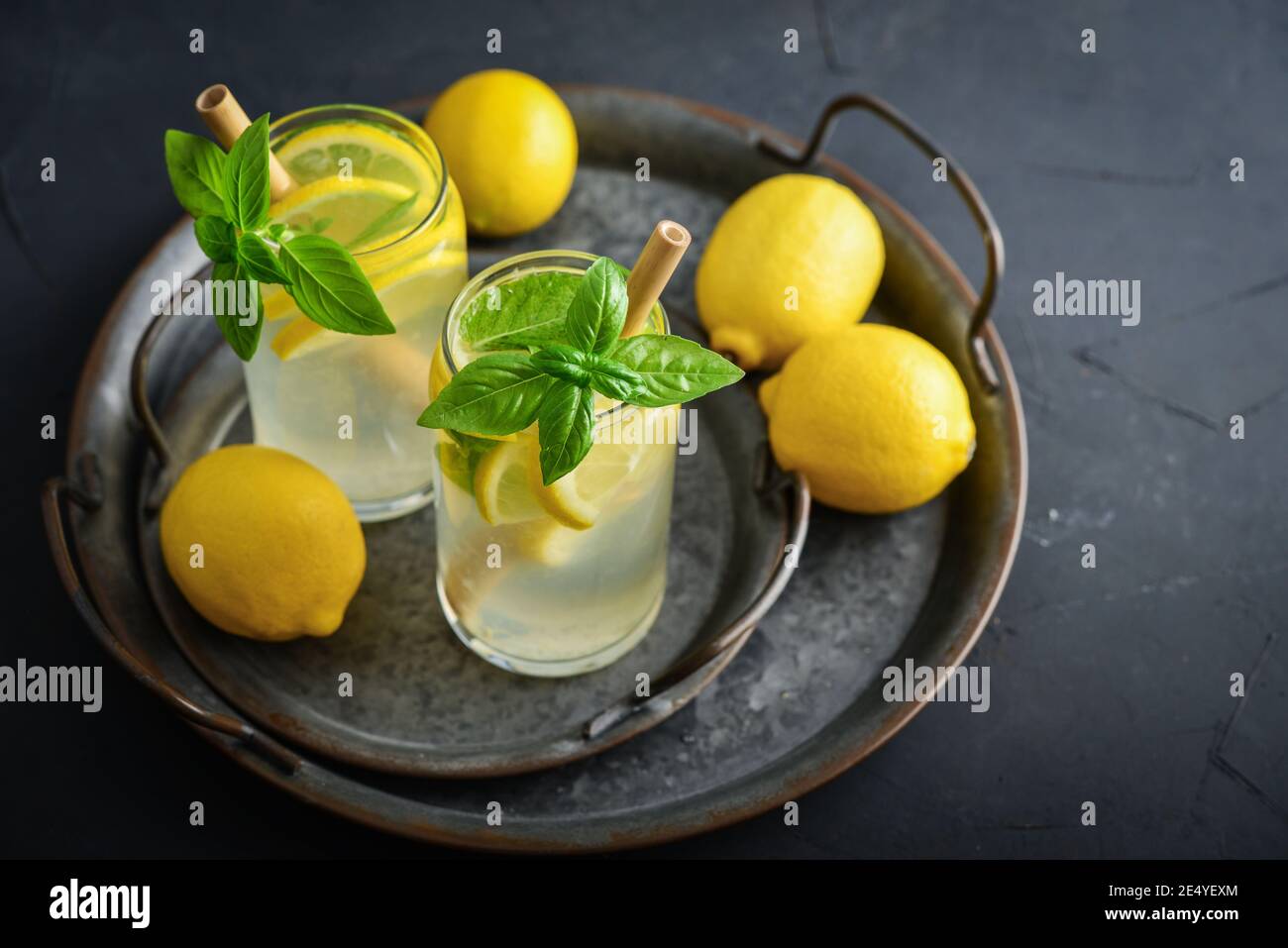 Limonade mit Zitrone und Basilikum, kaltes Erfrischungsgetränk in Gläsern auf schwarzem Hintergrund Stockfoto