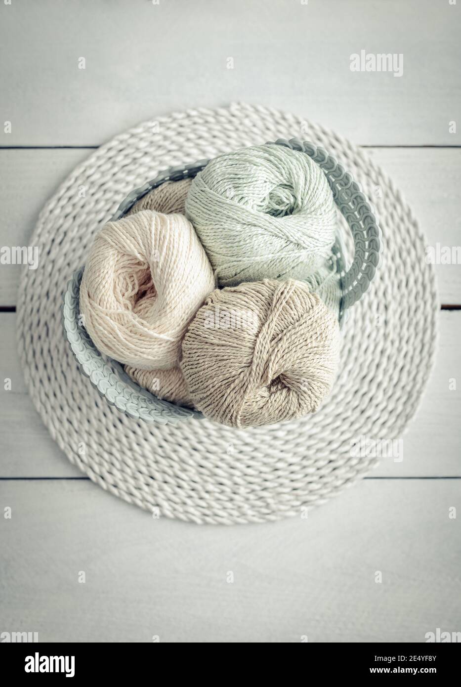 Farbige Garnkugeln und Stricknadeln im Korb auf hellem Hintergrund, Draufsicht Stockfoto