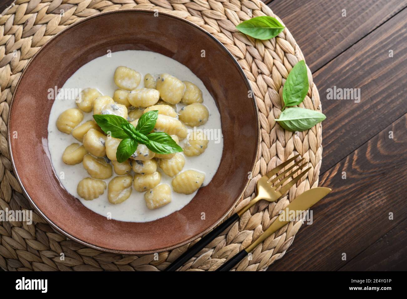 Hausgemachte Gnocchi mit cremiger Gorgonzola-Sauce in brauner Platte auf Holzhintergrund, Draufsicht Stockfoto