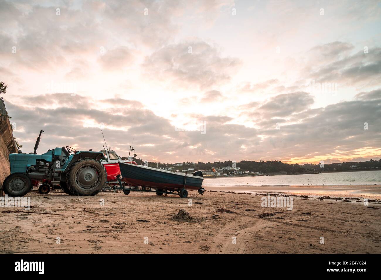 St Brelades Bay Kanalinsel Jersey Sonnenuntergang Sonnenaufgang dämmert atemberaubend Lebendige orange Himmel schöne Küste Sandstrand Morgen Traktoren Schleppen Boote Stockfoto