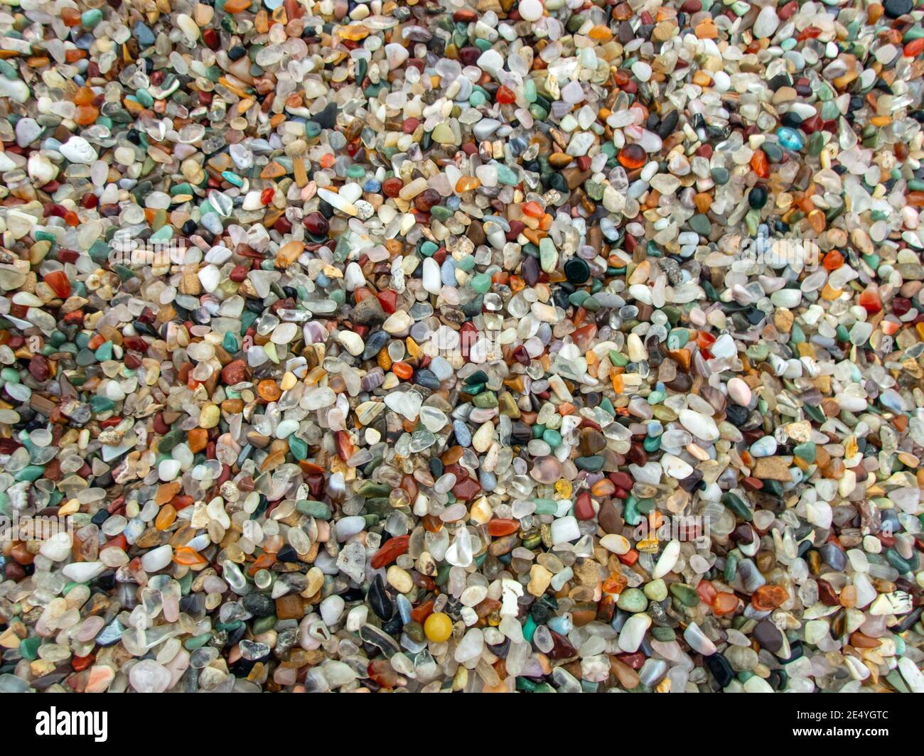 Ein Haufen voller kleiner Achatsteine macht einen ziemlich bunten Hintergrund oder Hintergrund mit viel Farbe, Formen und Größen. Leichter Bokeh-Effekt. Stockfoto