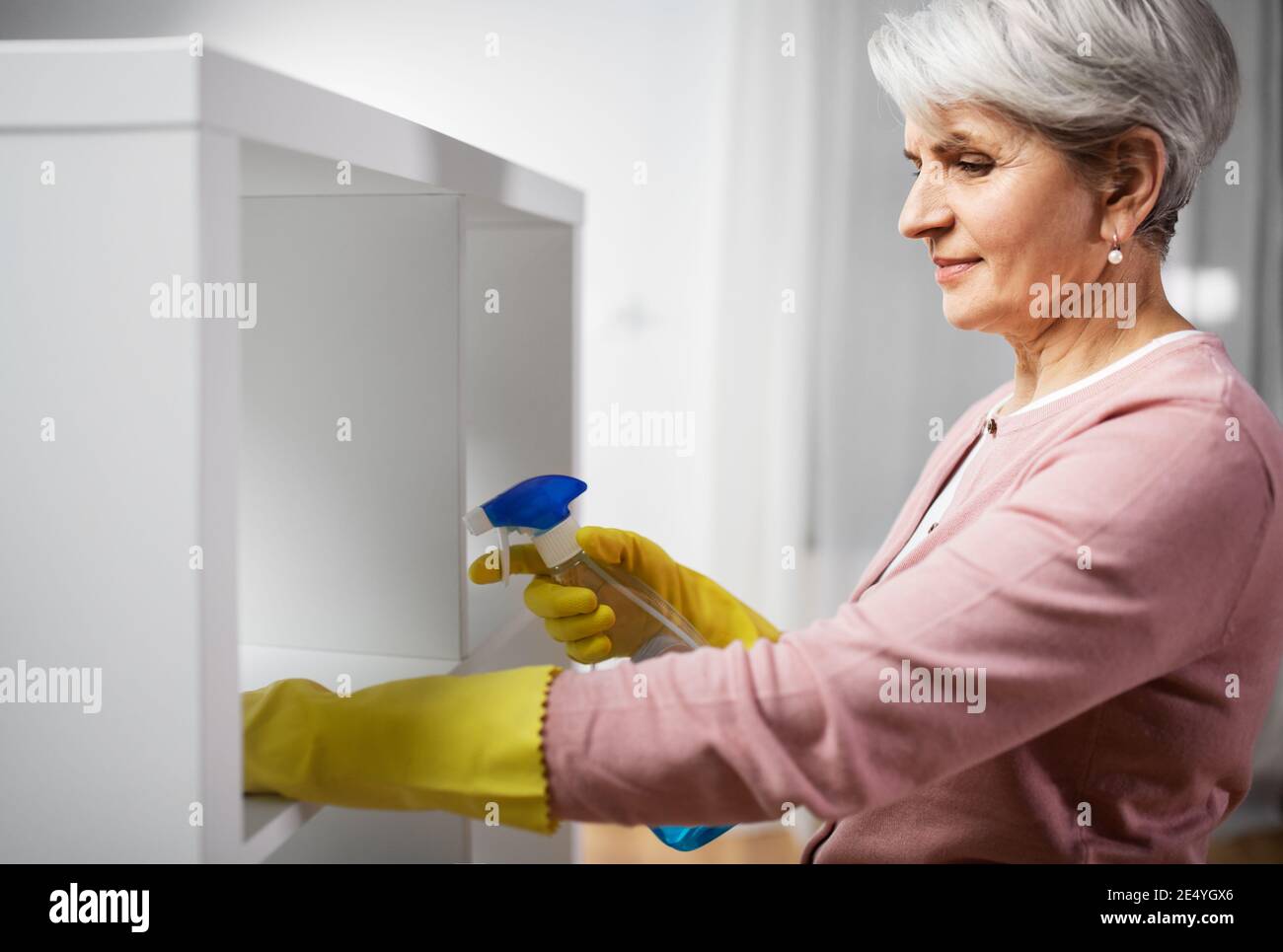 Ältere Frau Reinigungsgestell mit Waschmittel zu Hause Stockfoto