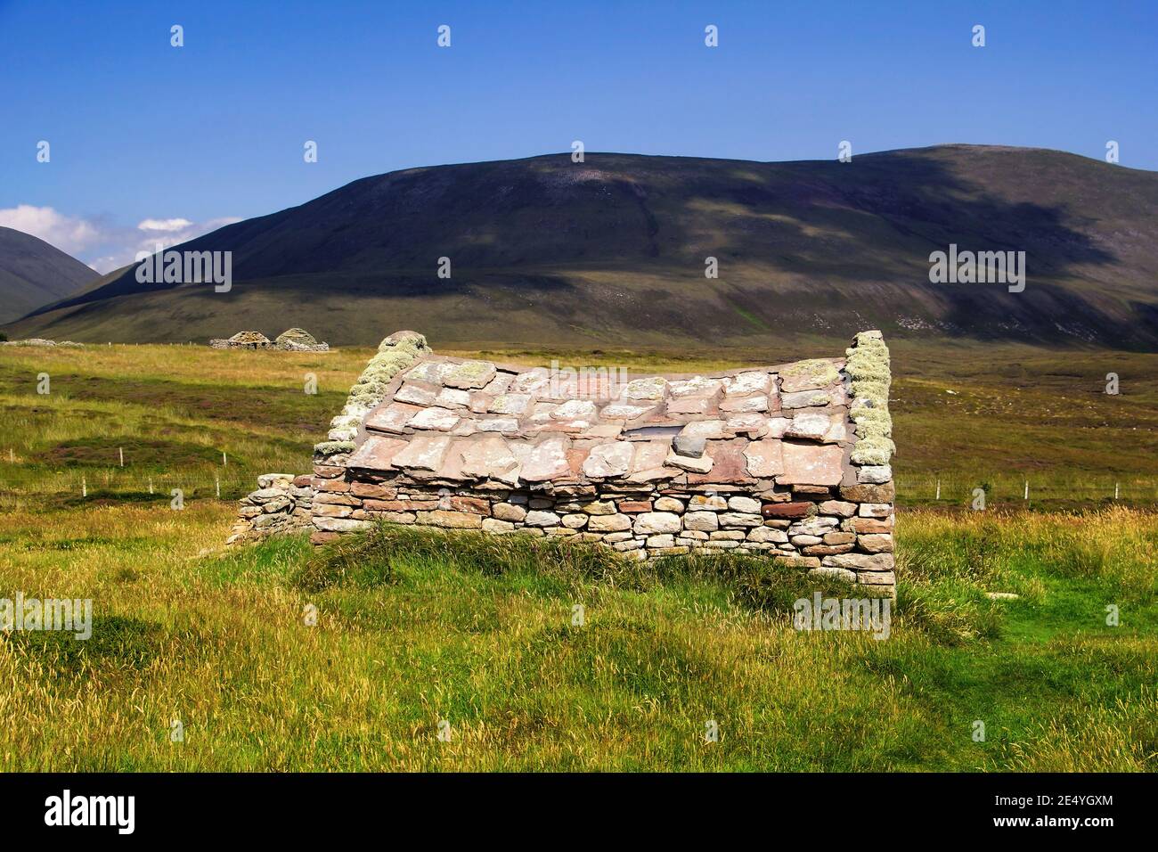 Traditionelles schottisches Bauernhaus aus Stein inmitten von grünem Gras Und dunkle Hügel im Hintergrund auf der schottischen Insel Hoy Am Sommertag von Orkney Stockfoto