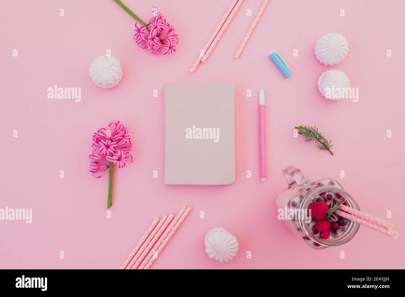 Leckere Smoothie mit Strohhalmen, Marshmallow, Tagebuch, Stift und rosa Blüten auf rosa. Flach liegend Stockfoto
