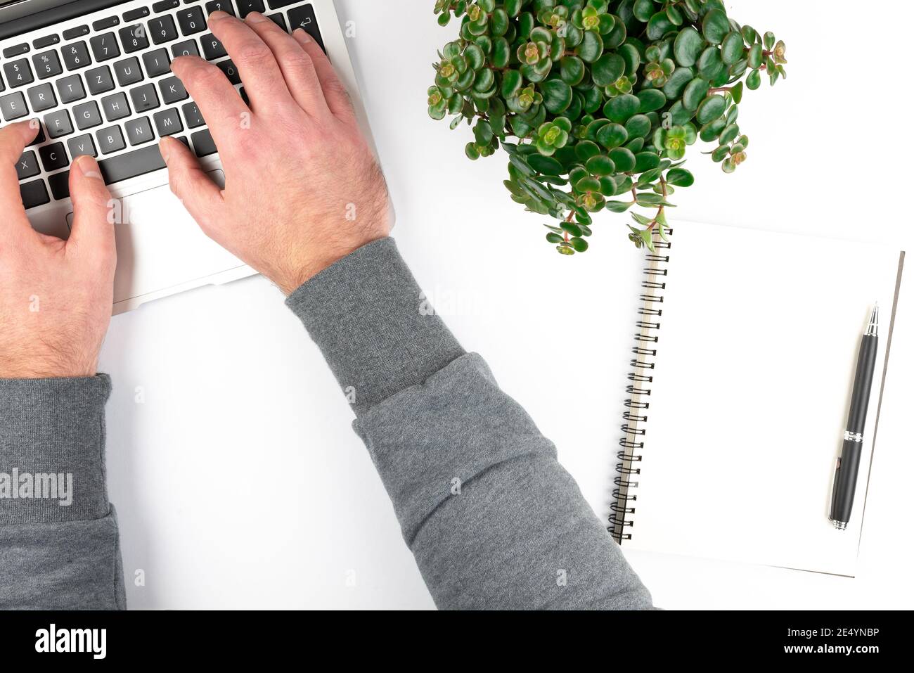 Overhead-Ansicht des sauberen weißen Büroschreibtisches mit Person, die auf einem Laptop-Computer tippt und von zu Hause aus arbeitet Stockfoto