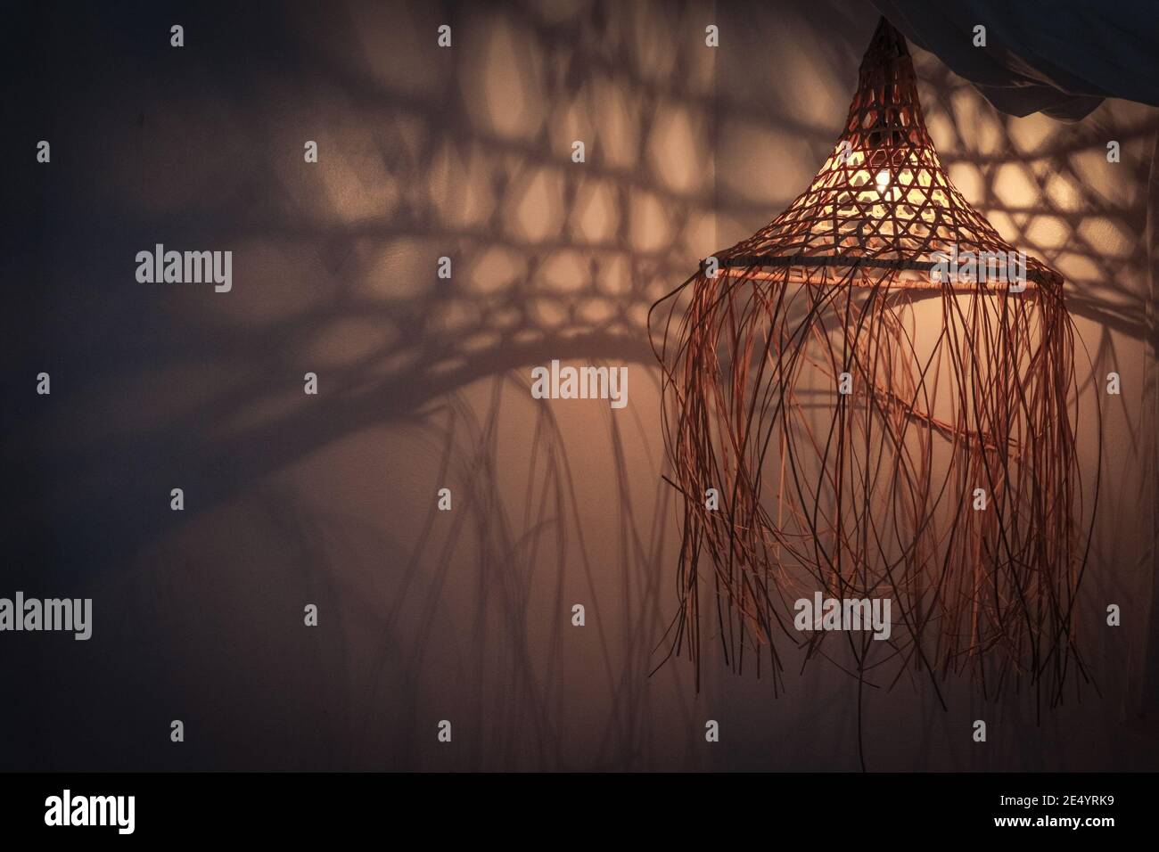 Bambuslampe in modernem Boho, tropischem, böhmischen Stil mit Schatten an der Wand Stockfoto