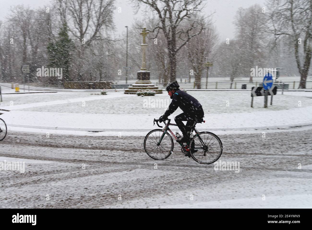 Radfahrer bei einem Kreisverkehr in einem Vorort während eines starken Schneefalls, Shepperton Surrey England Großbritannien Stockfoto