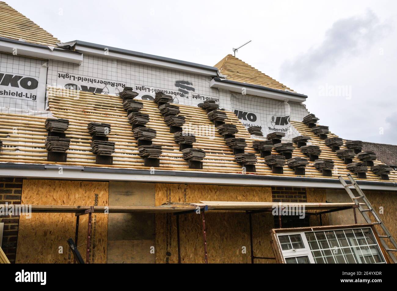 Eine Wohnhauserweiterung hat das Dach bereit für Fliesen mit Stapeln von Lehmziegeln ordentlich ausgelegt. Stockfoto