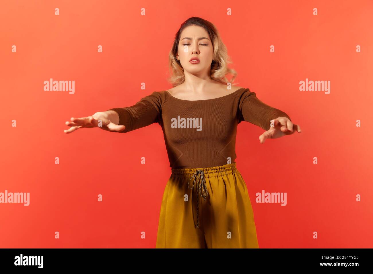Ich sehe nichts. Portrait der blonden Frau stehen mit geschlossenen Augen und ausgestreckten Händen, versuchen, Hindernisse beim Gehen blind zu finden. Innen Stockfoto