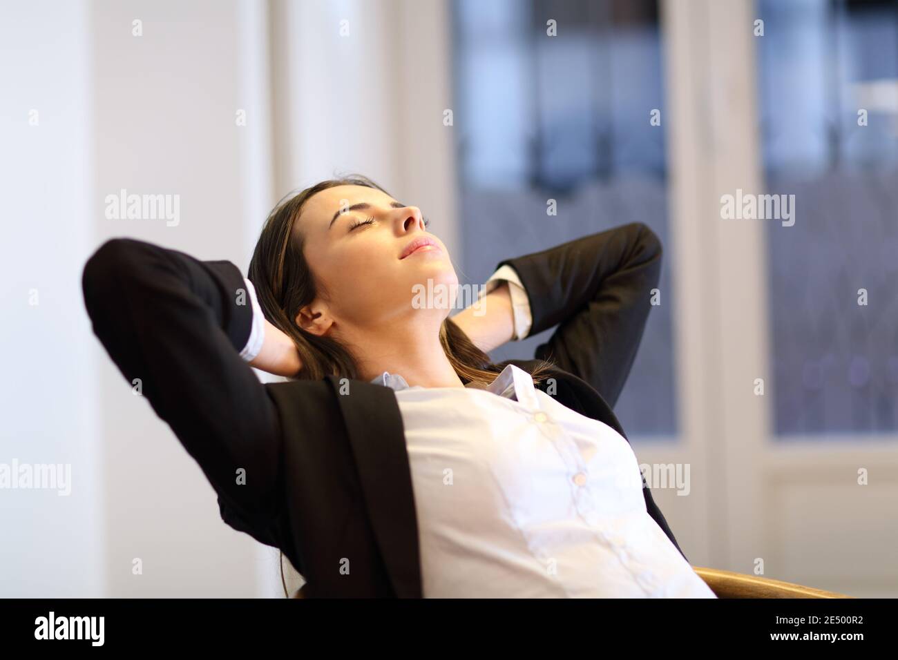Zufriedene Geschäftsfrau, die sich auf einem Stuhl im Büro entspannt Stockfoto
