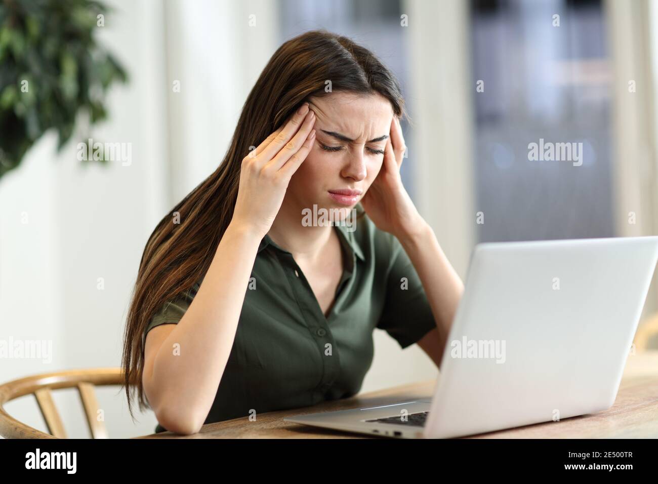 Gestresste Frau leiden Migräne mit einem Laptop in einem sitzen Tisch zu Hause Stockfoto