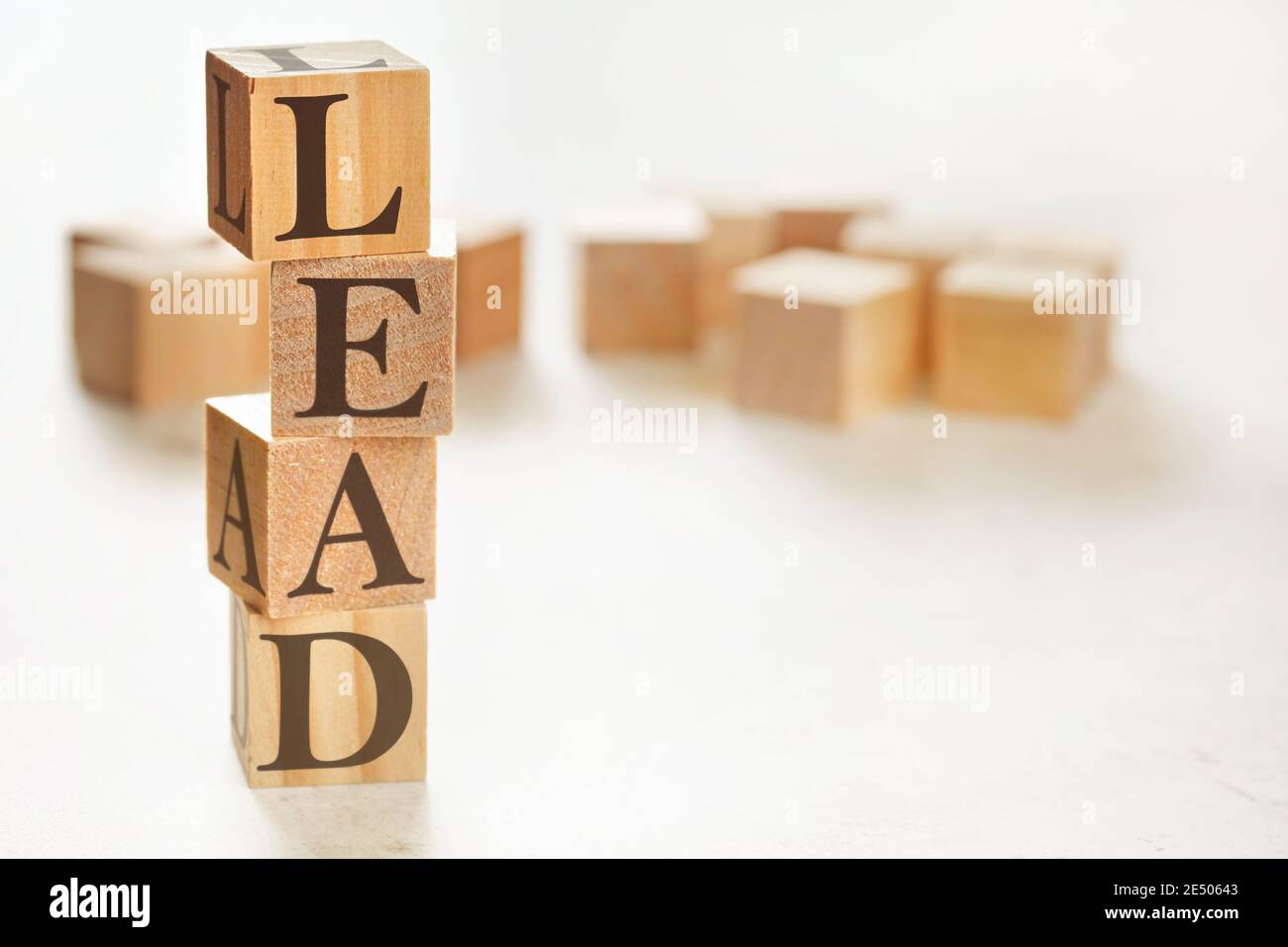 Vier Holzwürfel im Stapel mit Buchstaben FÜHREN darauf (Lernen, Bildung, Aktion, Entwicklung), rechts unten Platz für Text / Bild Stockfoto