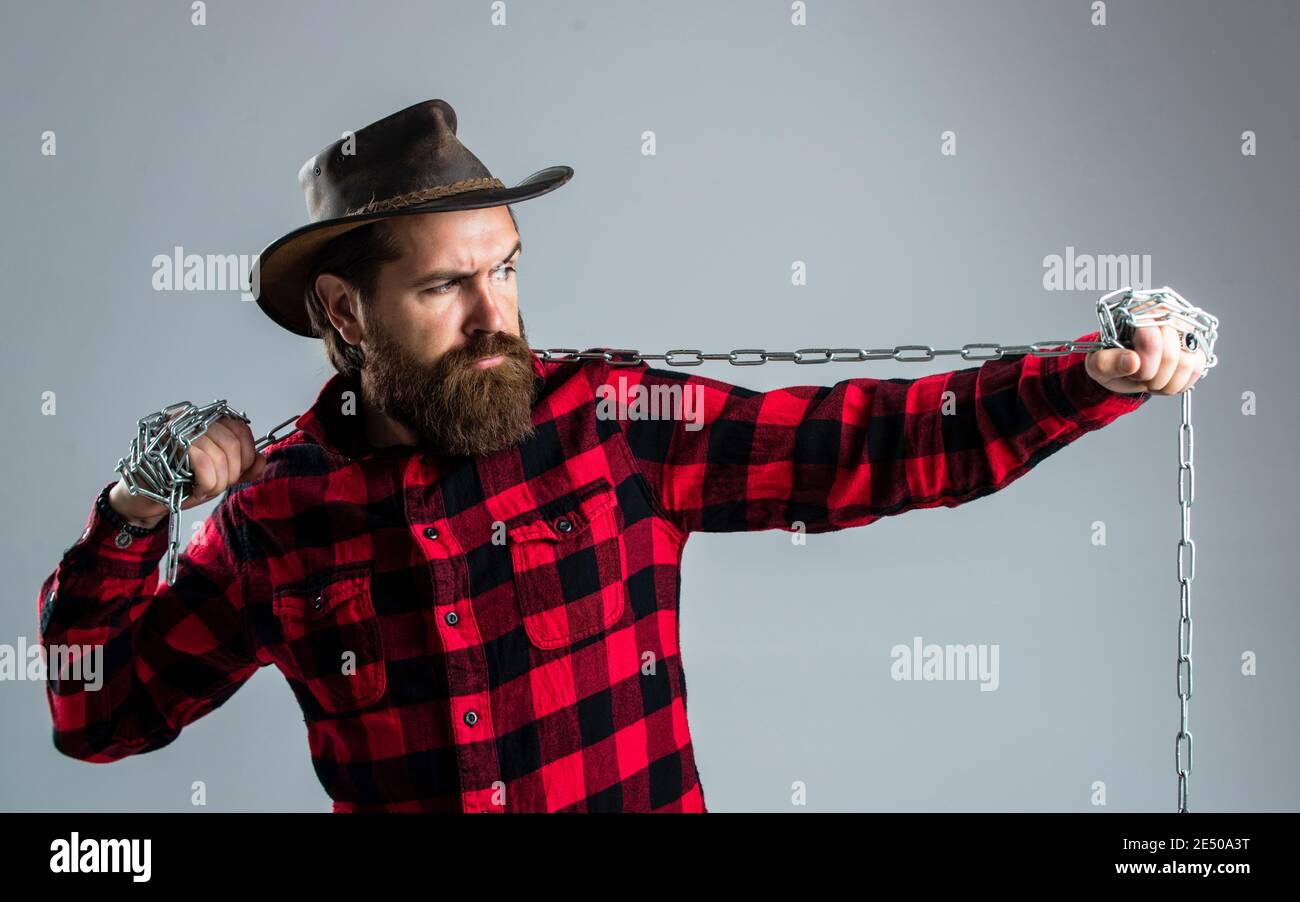 Cowboy Mann mit Bart und Schnurrbart ziehen Stahlkette, Routine auf Ranch. Stockfoto