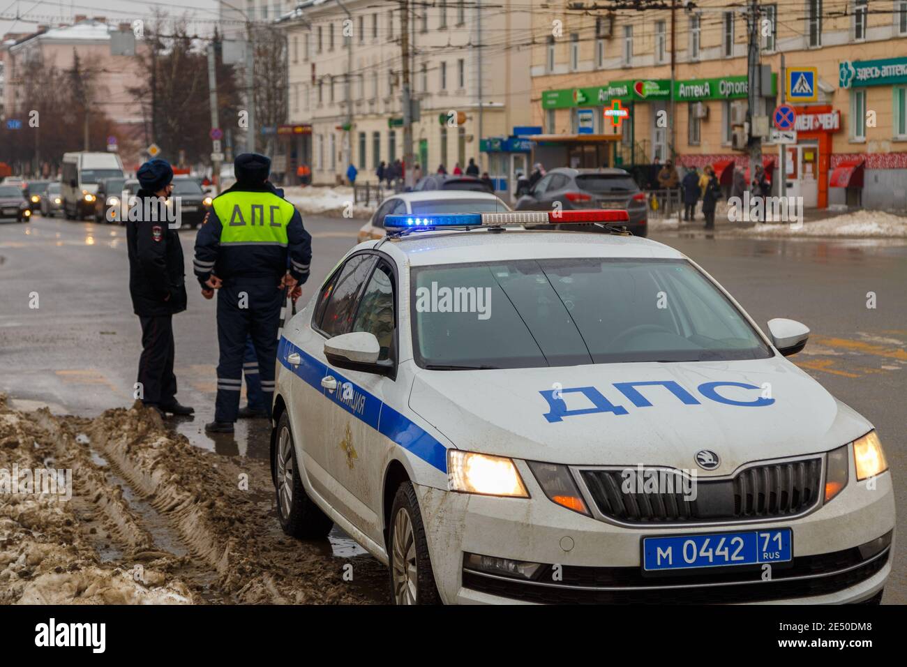 Russische Straßenpolizisten stehen in der Nähe von Patrouillenwagen und schmutzigem Schnee auf der winterlichen Stadtstraße - Nahaufnahme mit selektivem Fokus auf Dachlampe. Buchstaben DPS mea Stockfoto