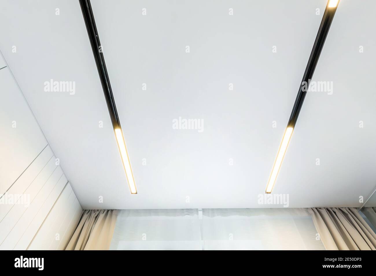 Abgehängte Decke mit Halogenstrahlern und Trockenmauerkonstruktion im leeren Raum in Wohnung oder Haus. Stretchdecke weiß und komplex. Stockfoto