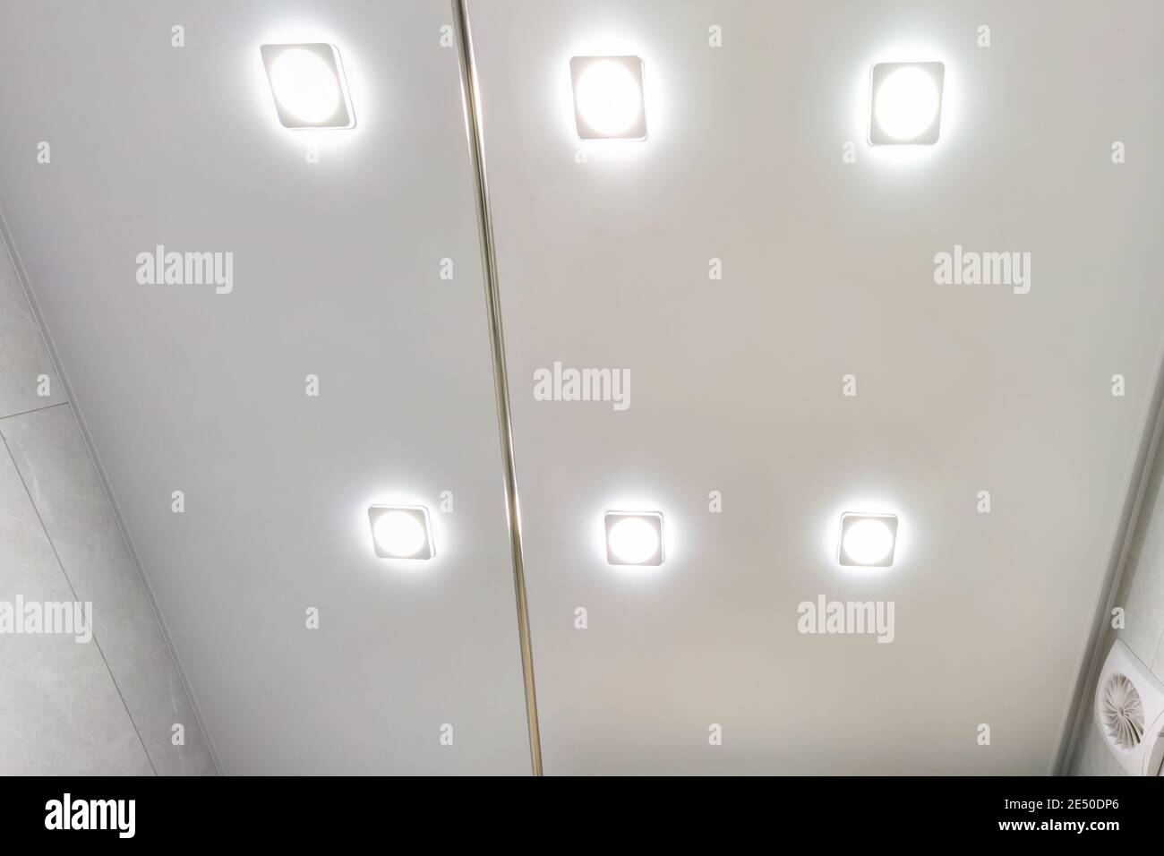 Abgehängte Decke mit Halogenstrahlern und Trockenmauerkonstruktion im leeren Raum in Wohnung oder Haus. Stretchdecke weiß und komplex. Stockfoto
